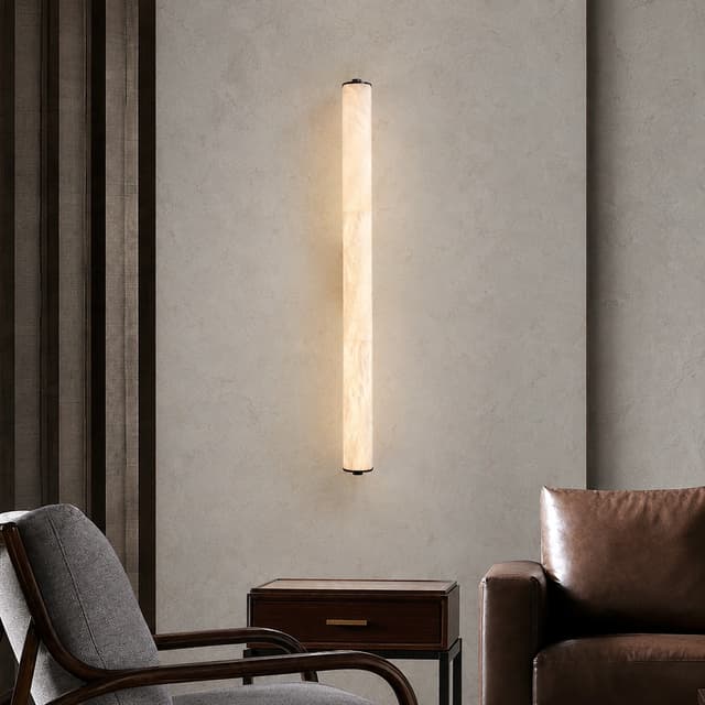 Slim vertical cylinder wall sconce glowing in a modern living room seating area