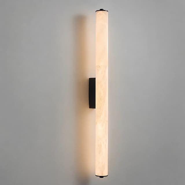 Long vertical alabaster style wall sconce with warm glow and black metal mounting plate