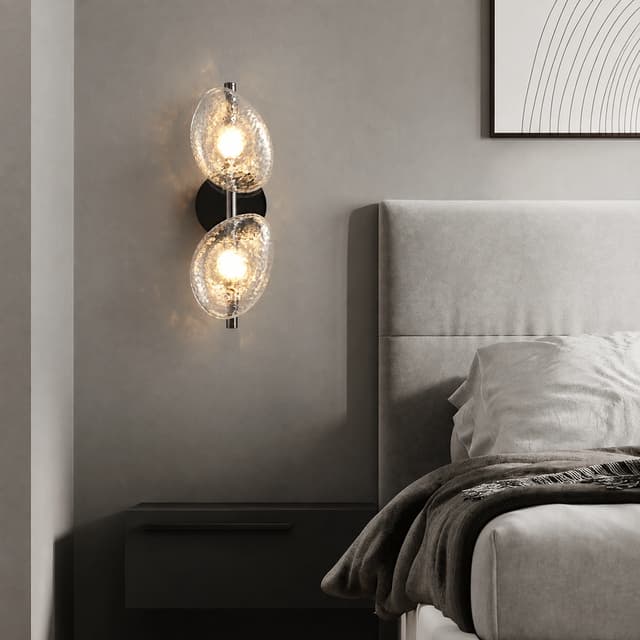 Clear textured glass double wall sconce beside a modern bedroom bed with warm ambient lighting