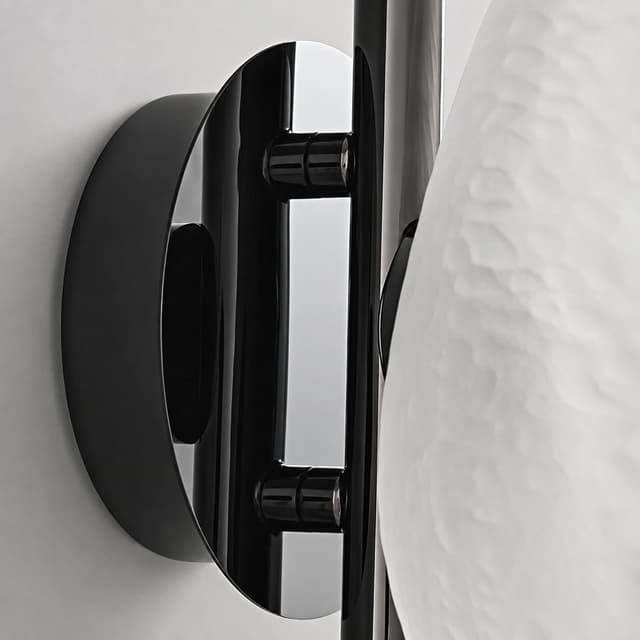 Close up of glossy black metal backplate and mounting structure on modern glass wall sconce