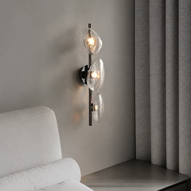 Three light textured clear glass wall sconce used as a sculptural accent light in a modern interior