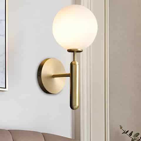 Brass finish opal glass wall sconce installed in a bright living room setting