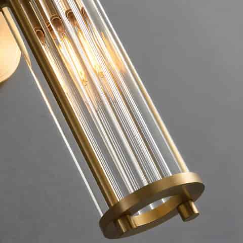 Close up of illuminated clear vertical glass rods on a brass finish wall sconce