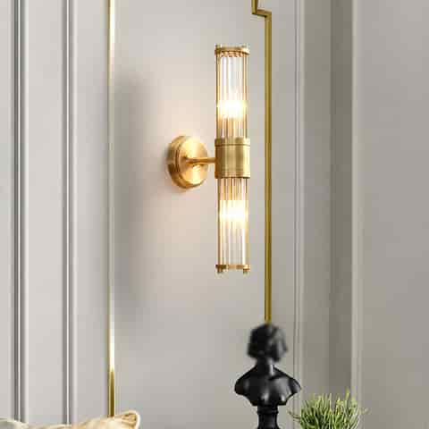 Vertical brass finish glass rod wall sconce styled in an elegant modern interior