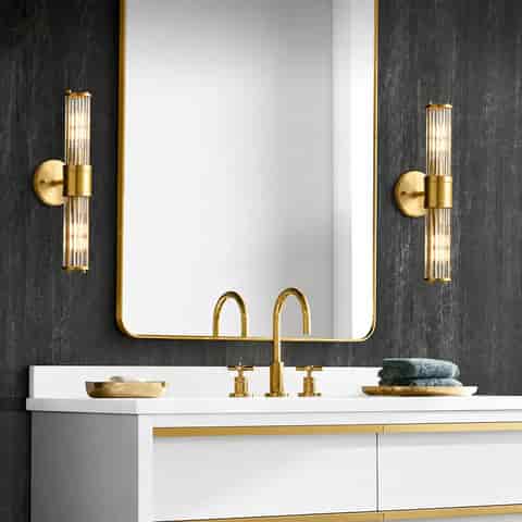 Pair of brass finish glass rod wall sconces beside a modern bathroom vanity mirror