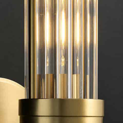 Detail of warm bulbs glowing through clear glass rods on a brass finish wall light