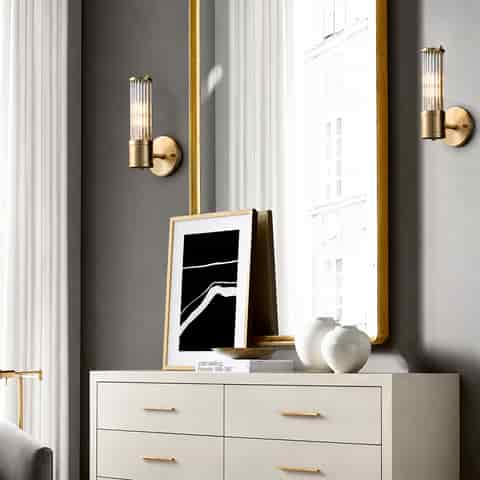 Pair of compact brass finish glass rod sconces framing a large bedroom mirror