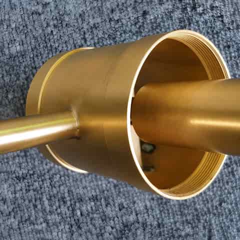 Close up of brass finish cylindrical center housing and wall arm construction