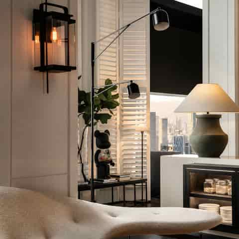 Sculptural black ceramic table lamp with tapered beige fabric shade in a modern apartment