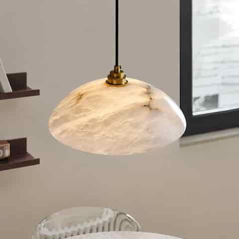 Alabaster dome pendant light casting a warm glow above a light wood dining table