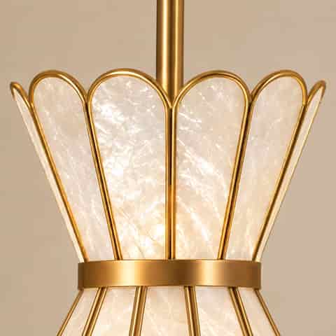 Close up of textured natural shell panels and brushed gold metal frame on a decorative wall sconce