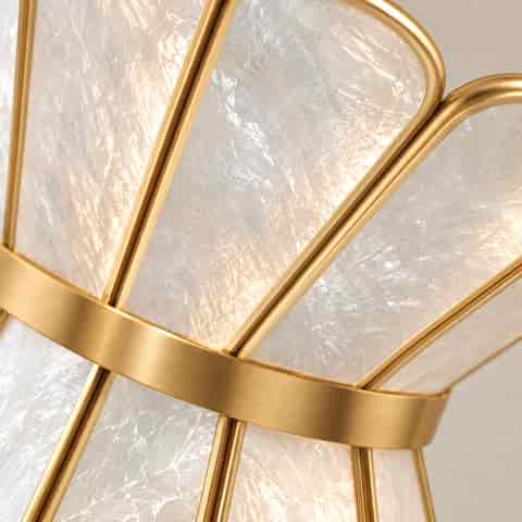 Sculptural shell wall sconce with translucent natural shell panels and curved gold tone arm