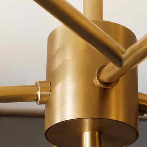 Close up of brushed gold tone metal hub on a modern branch chandelier