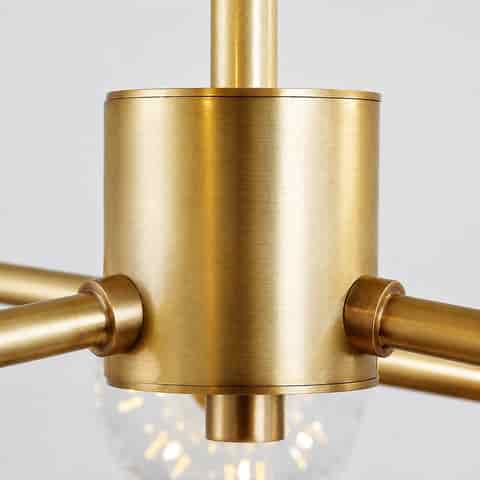 Close up of brushed gold tone chandelier body and branching metal arm connections