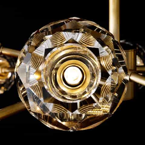Close up of illuminated faceted clear globe shade on a gold branch chandelier