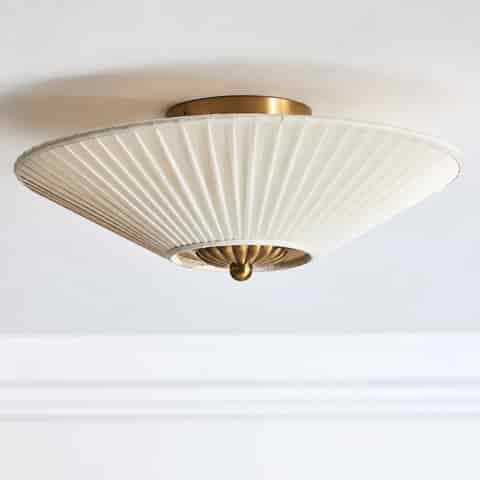 Close up of the pleated ivory fabric shade and sculptural copper tone floral center detail on a modern Art Deco ceiling light