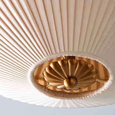 French Art Deco copper finish flush mount ceiling light with an ivory pleated fabric shade and sculptural brass tone center detail