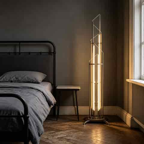 Sculptural geometric glass floor lamp illuminating a modern bedroom with warm ambient light