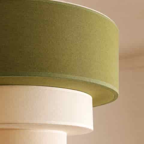 Close up of olive green and cream woven fabric shades on a three tier pendant light