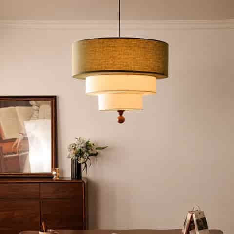 Olive green three tier fabric drum pendant light with cream layered shades and warm illumination