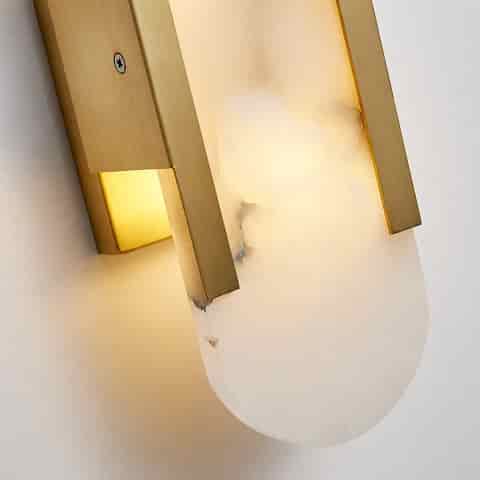 Close up of natural alabaster wall sconce with gold finish metal frame and warm glow