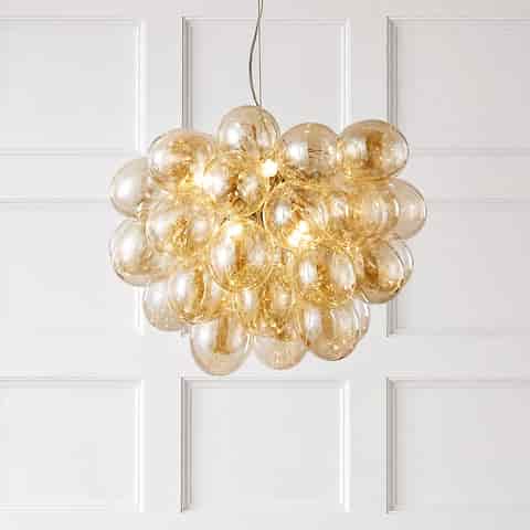 Amber bubble globe cluster chandelier glowing against a white paneled wall