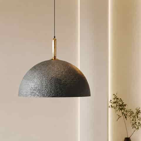 Black textured dome pendant light with gold tone accent in a warm minimalist interior