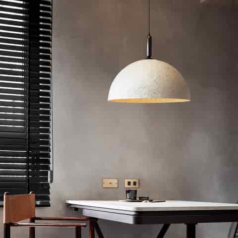 White textured dome pendant light above a modern dining table with warm downward lighting