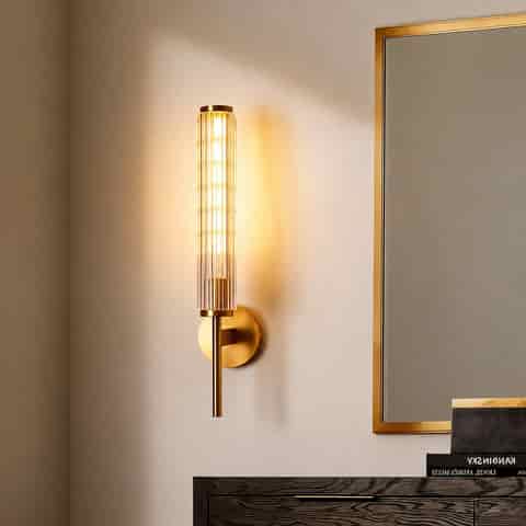 Gold fluted glass and copper wall sconce beside a modern framed mirror