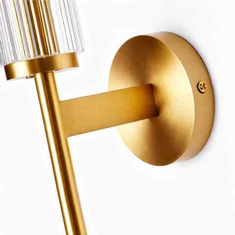 Close up of gold finish copper wall sconce with round backplate and fluted glass