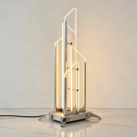 Modern geometric glass LED table lamp with warm integrated lighting and a sculptural brushed metal frame