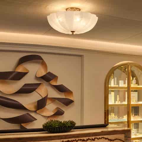 French Art Deco copper and glass ceiling light glowing warmly in an elegant luxury interior