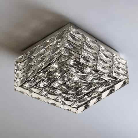 Close up of faceted clear crystal panels on a modern square flush mount ceiling light with strong light refraction